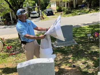 Picture shows Public Works employee examining a cemetery burials map in front of a monument.